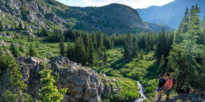 hikers looking at creek and mountains